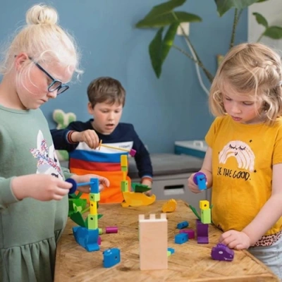 Kinderen in Nederland spelen het BS Toys Draak Steken stapelspel ter bevordering van de fijne motoriek