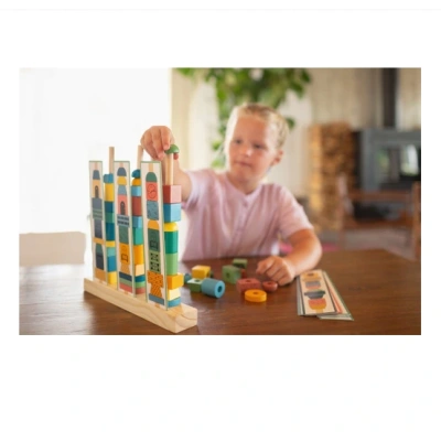Jongen speelt het spel stapeltorens met alle houten blokken.