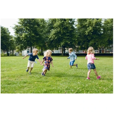 Kinderen spelen Staarten Tikkertje op het grasveld bij school